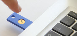 Picture of hand tapping the key icon on a U2F token inserted in a USB port on a computer