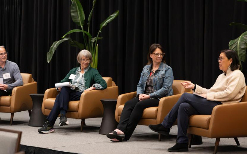four panelists sit in chairs on a stage