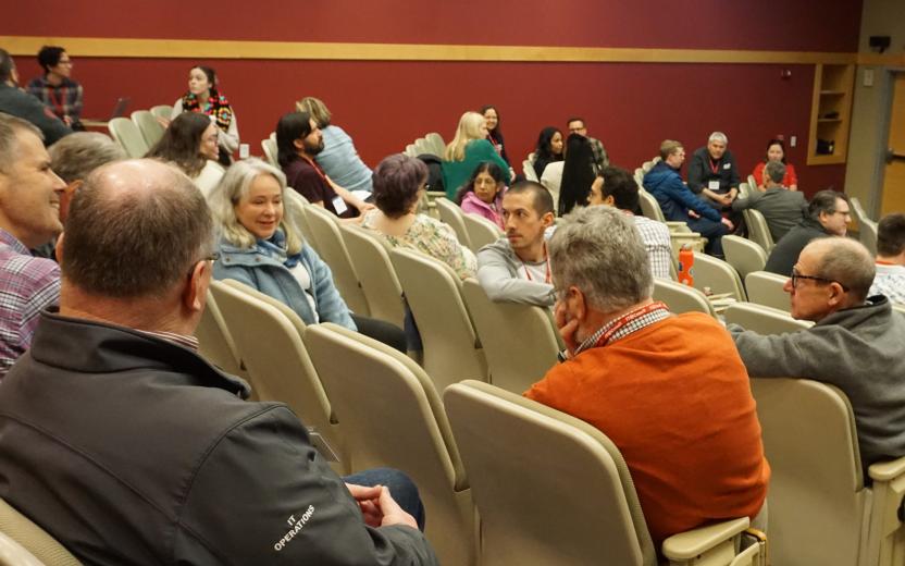 across a classroom, small groups of IT professionals discuss topics