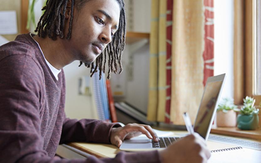Student taking notes at the computer