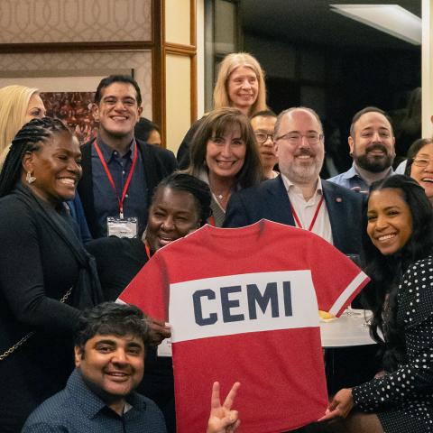 a group of people pose with a CEMI jersey