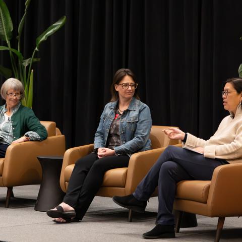 four panelists sit in chairs on a stage