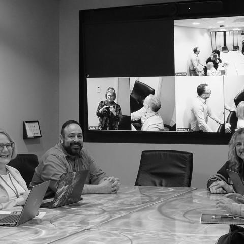 six colleagues smile for a photo in the middle of a small group discussion