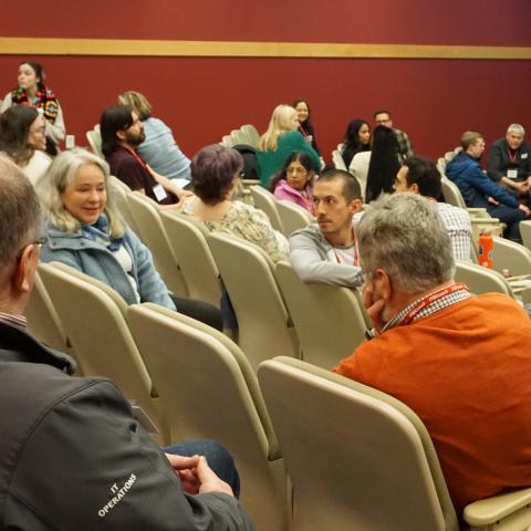 across a classroom, small groups of IT professionals discuss topics