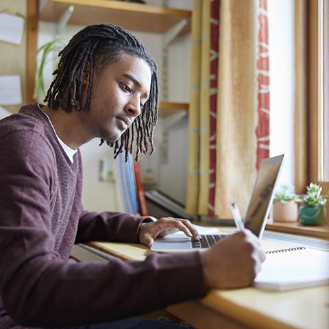 Student taking notes at the computer